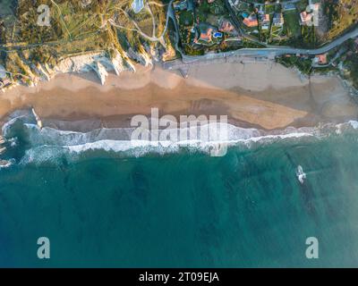 Vista aerea delle onde del mare che si precipitano verso la spiaggia sabbiosa dei Paesi Baschi nelle soleggiate giornate estive Foto Stock