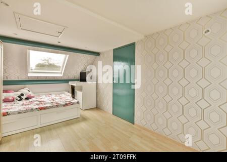 Interni di una spaziosa camera da letto mansardata con comodo letto e scrivania dalla finestra in una casa contemporanea con tappezzeria Foto Stock