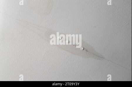 Perdite d'acqua dal soffitto del muro a secco nella stanza di casa, danni causati dall'acqua. Gocciolamento d'acqua dovuto a crepe. Foto Stock