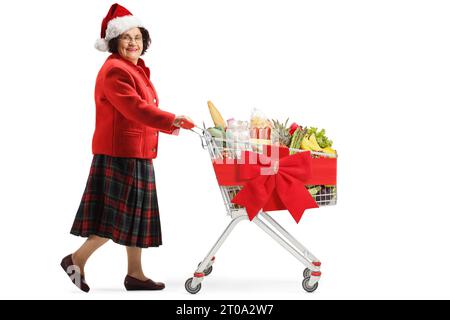 Foto completa di una donna anziana con il cappello di babbo natale che spinge un carrello isolato su sfondo bianco Foto Stock