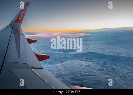 Ala jet in alto sopra le nuvole durante un volo serale. Foto Stock