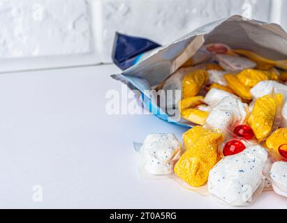 capsule per lavare i piatti davanti a una confezione aperta su sfondo bianco. Foto di alta qualità Foto Stock