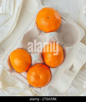 I mandarini freschi sono collocati su uno sfondo di tessuto bianco. Foto di alta qualità Foto Stock