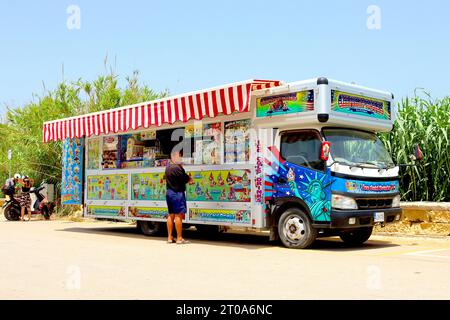 Un cliente si stupisce dell'enorme selezione di bevande fredde e ghiacciate in offerta presso il Champions Ice Cream Truck, parcheggiato a Ramla Bay, Gozo, Malta, giugno 2022. Foto Stock