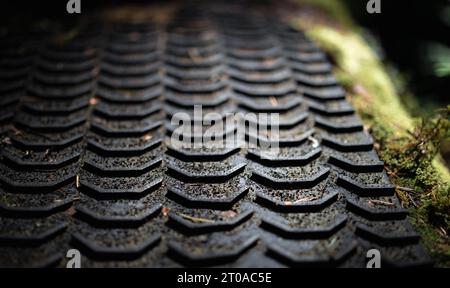 Struttura del tappetino in gomma nera, primo piano. Texture di sfondo astratta. Tappetino con fili lunghi in gomma utilizzato nella costruzione di sentieri per mountain bike. Messa a fuoco selettiva in Foto Stock