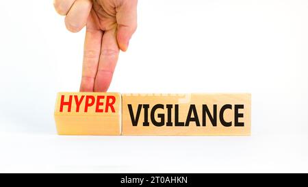 Simbolo di vigilanza o ipervigilanza. Parole concettuali Vigilance Hypervigilance su blocchi di legno. Splendido sfondo bianco. Mano psicologa. Psicologia Foto Stock