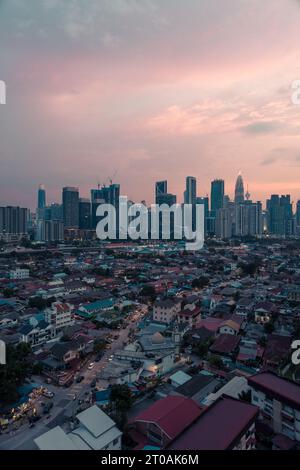 Vista su Kampung Datuk Keramat al tramonto con lo skyline del centro di Kuala Lumpur e le torri Petronas sullo sfondo Foto Stock