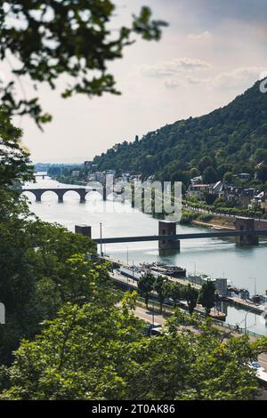 Accattivante Heidelberg: Una vista pittoresca del fiume Neckar, il Ponte Vecchio, le case storiche e le maestose montagne che formano un paesaggio urbano mozzafiato Foto Stock