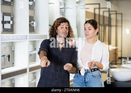 Donna e uomo che discutono della lista di shopping e che indicano qualcosa nel deposito Foto Stock