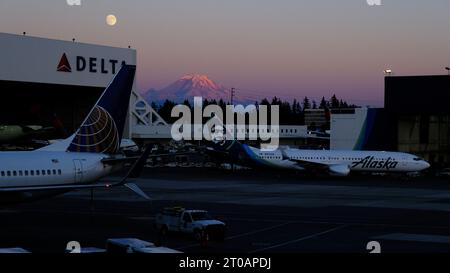 Luna piena che sorge sull'aeroporto SeaTac a sud di Seattle con il monte Rainier si illumina al tramonto in tarda serata d'estate Foto Stock