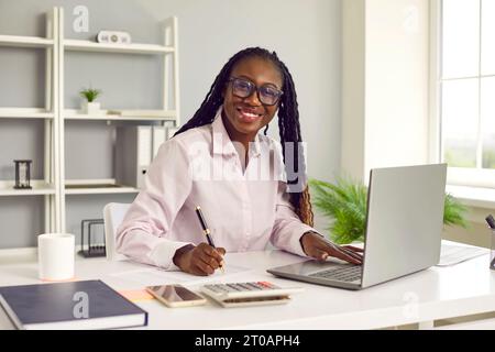 Ritratto di un'amichevole consulente finanziaria femminile dalla pelle scura che lavora con i dati contabili aziendali. Foto Stock