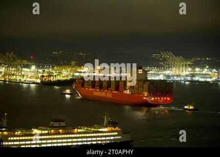 Attracchi per navi portacontainer la mattina presto nel porto di Seattle con l'aiuto di diversi rimorchiatori Foto Stock