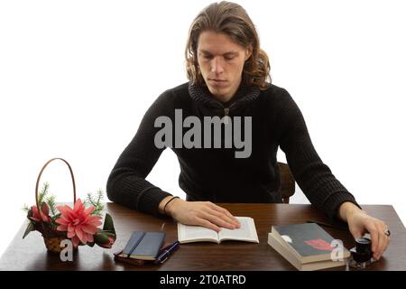 Uno studente siede a un tavolo e legge un libro Foto Stock