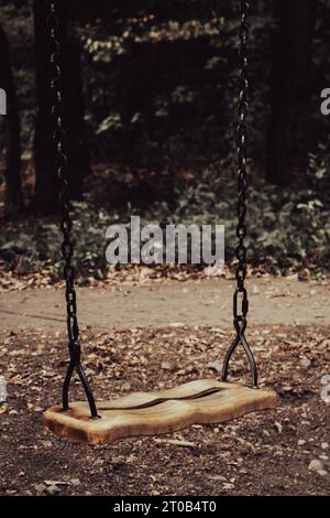 Altalena vuota sul parco giochi. Vecchio parco giochi abbandonato nella foresta. Un posto spaventoso e tranquillo. L'orrore oscilla senza figli. Concetto di depressione autunnale. Foto Stock