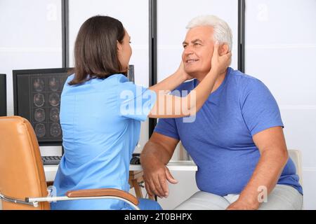 Fisioterapista femminile che esamina il collo di un paziente anziano in un centro di riabilitazione Foto Stock
