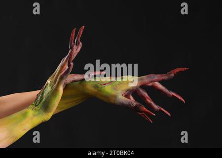 Mani di strega con artigli su sfondo nero. Festa di Halloween Foto Stock