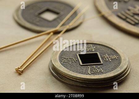 Aghi per agopuntura e monete antiche su carta, primo piano Foto Stock