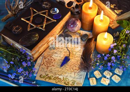 Libro magico nero di incantesimi, rune e candele su un rituale tavolo da strega. Occulta, esoterica e predica la vita morta. Sfondo mistico con vintage Foto Stock