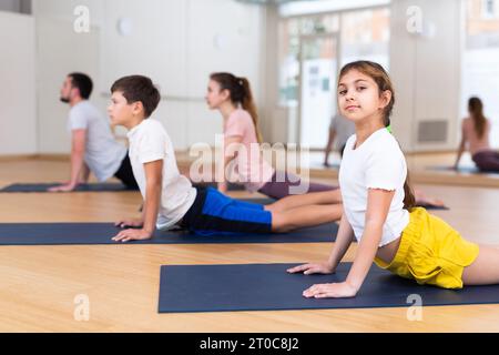 Ragazza che pratica yoga in studio con la famiglia Foto Stock