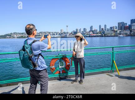 I turisti che scattano foto utilizzando lo smartphone sul traghetto di Elliott Bay. Lo skyline di Seattle e lo storico Space Needle sullo sfondo. Seattle. Lavaggio Foto Stock
