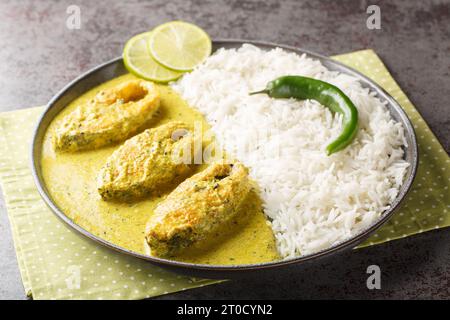 Pesce di Hilsa in salsa di senape o salsa Shorshe Ilish servito con primo piano di riso bianco sul piatto sul tavolo. Orizzontale Foto Stock