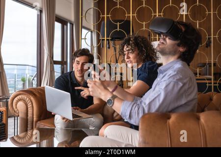 Uomo d'affari che indossa un simulatore di realtà virtuale accanto ai colleghi al chiuso Foto Stock