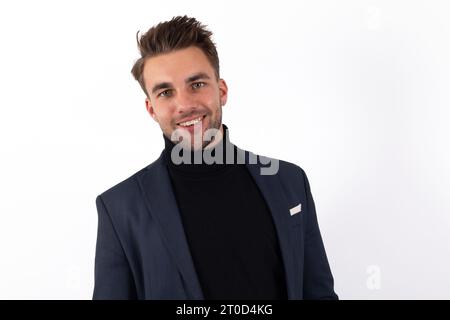 Un bel giovane uomo, vestito con una giacca e una polo sul collo, sorride radiosamente in un accattivante primo piano Foto Stock