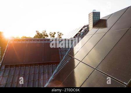 Pannelli solari sul tetto di una casa unifamiliare sostenibile al tramonto Foto Stock