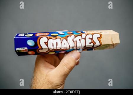 Parigi, Francia - 12 luglio 2023: Contiene un pacchetto di Smarties, che sfoggia le caramelle dai colori vivaci su uno sfondo grigio tenue per un contrasto visivo di impatto Foto Stock