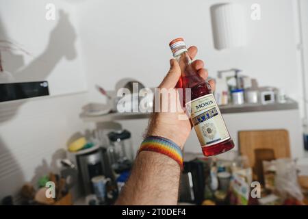 Parigi, Francia - 12 giugno 2023: Una mano maschile afferra una bottiglia di aperitivo Monin, un prodotto di un'impresa francese nota per la creazione di sciroppi e liquori principalmente per il settore alberghiero Foto Stock