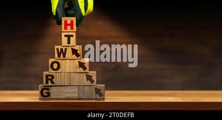 Guanti disposti a mano in blocchi di legno con simbolo di crescita del testo e frecce, sopra un tavolo o una scrivania di legno con spazio per la copia. Foto Stock