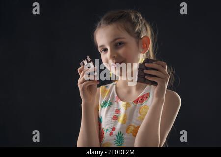 Cioccolato e carino affamato piccola donna ritratto. Bella ragazza pronta a mangiare cioccolato bar. Foto Stock