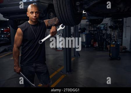 Afro-americano di un'officina di riparazione di automobili che tiene due grandi chiavi Foto Stock