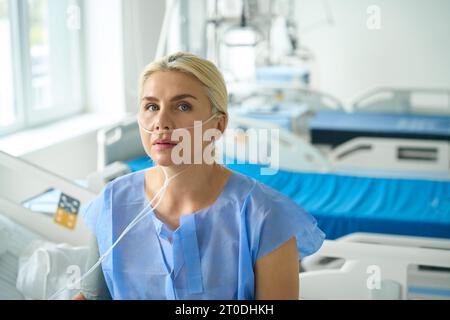 Bella femmina siede su un letto d'ospedale in terapia intensiva Foto Stock