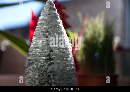 Un piccolo albero artificiale adornato di fiori bianchi della neve cattura lo spirito del natale, i suoi rami pieni di gioia festosa Foto Stock