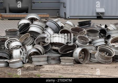 Pile di cerchi per auto d'epoca presso lo scrapheap Junkyard. Impilamento di vecchie ruote scartate, industria del riciclaggio dei metalli. Foto Stock