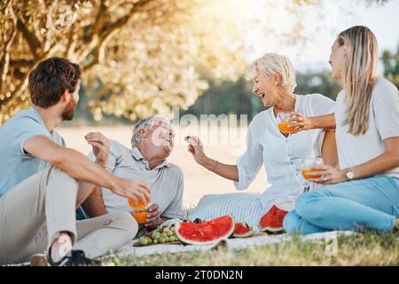 Cibo da picnic, famiglia felice e genitori anziani, figlia e figlio che si divertono, mangiano uva e si godono la natura, il parco o il benessere. Frutta, amore e relax Foto Stock