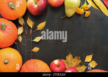 Il Ringraziamento e il design autunnale. Sfondo autunnale con zucche mature, foglie, mele e pere. Telaio per il raccolto autunnale su sfondo di legno scuro Foto Stock