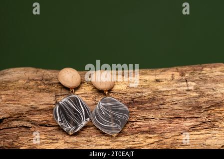 Orecchini eleganti su rametto di legno su sfondo beige. Concetto di fotografia di moda per gioielli. foto studio Foto Stock