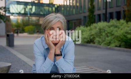 Turbato pensivo triste preoccupata vecchia donna d'affari caucasica senior pensando pensieri di dolore signora matura contemplare all'aperto preoccupare il fallimento della carriera Foto Stock