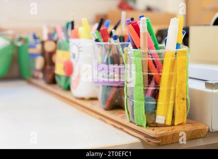 Molte penne da colorare e matite in portamatite su un tavolo di lavoro in classe d'arte, studio o scuola. Texture di sfondo artistico e artigianale. Progetto fai da te o bambini Foto Stock