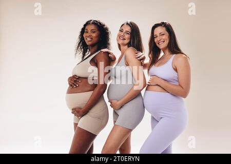 donne in gravidanza che partecipano a una lezione di yoga prenatale diversa, che si uniscono al loro viaggio condiviso verso la maternità. Amici in uno studio con fitness cl Foto Stock