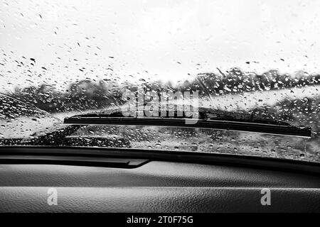 Gocce di pioggia sul parabrezza di un'auto, vista dall'interno. Foto in bianco e nero Foto Stock