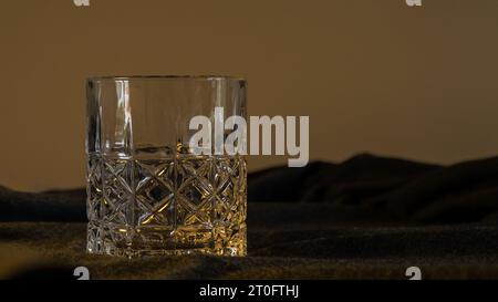 Un solitario bicchiere di whisky, adagiato su un elegante sfondo grigio-nero, che incarna la raffinatezza e l'essenza della contemplazione Foto Stock