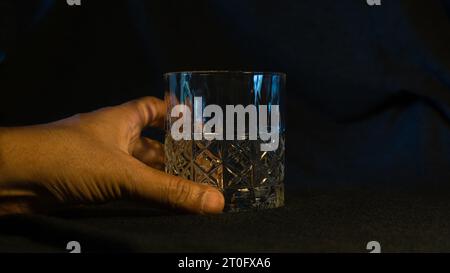 Un solitario bicchiere di whisky, adagiato su un elegante sfondo grigio-nero, che incarna la raffinatezza e l'essenza della contemplazione Foto Stock