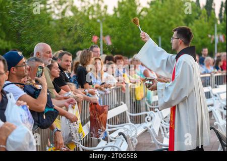 Un sacerdote che benedice gli articoli religiosi dei fedeli dopo la Santa Messa di sera a Medjugorje. Foto Stock