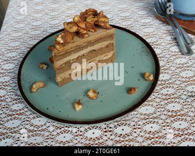 Torta allo strato di noce di anacardi e crema marrone in un piatto rotondo blu Foto Stock