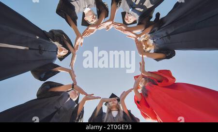 I laureati fanno un grande cerchio dalle loro mani. Foto Stock