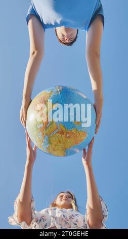 Una ragazza e un ragazzo girano un globo del mondo. Il concetto di pace e creazione. Foto Stock