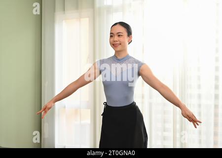 Giovane ballerina dedicata che pratica movimenti di danza in uno studio luminoso. Concetto di danza, arte, educazione e flessibilità Foto Stock